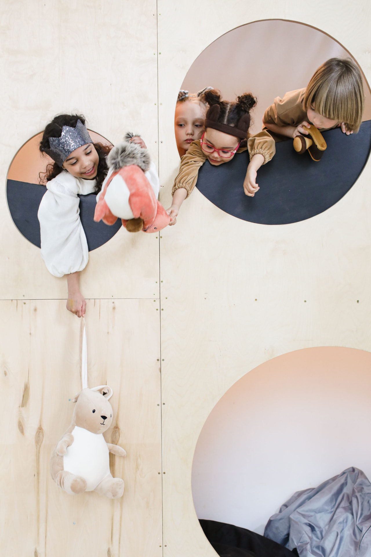 Des enfants jouent dans une structure en bois avec des hublots